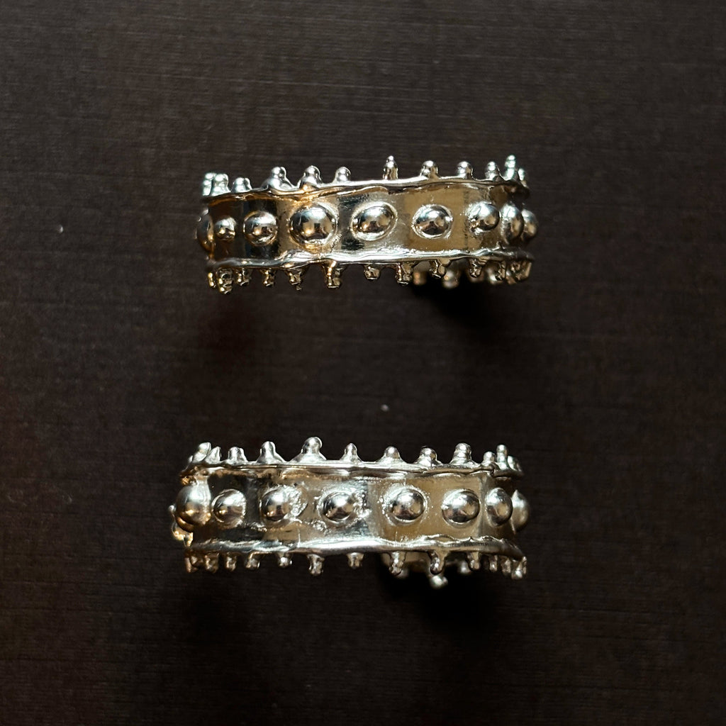 Large chunky textured silver hoops on a brown background. 