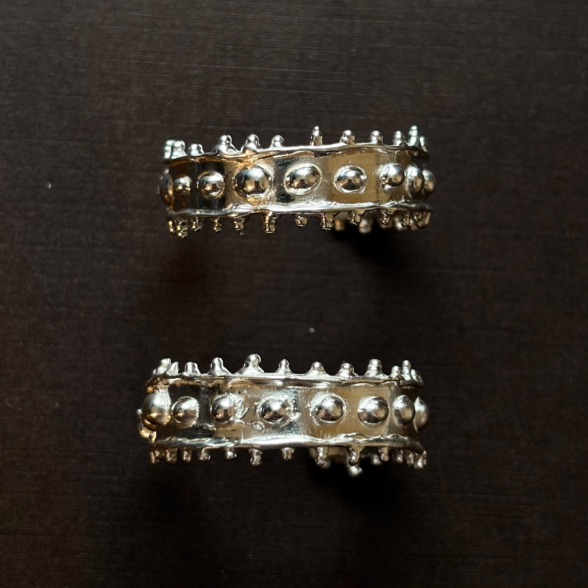 Large chunky textured silver hoops on a brown background. 