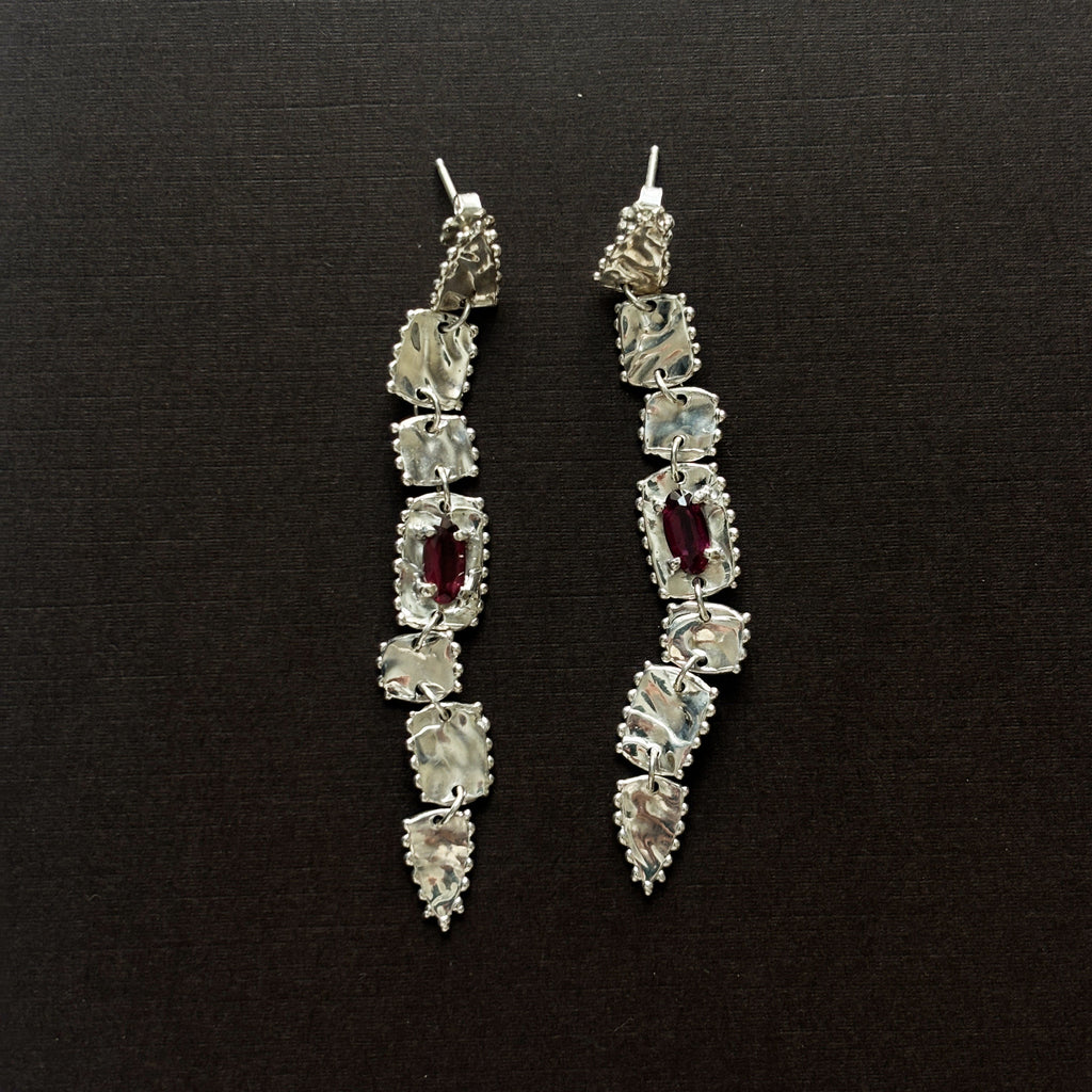 pair of sterling silver long drop earrings  with elongated rhodolite garnets (deep purple/pink) brown background 