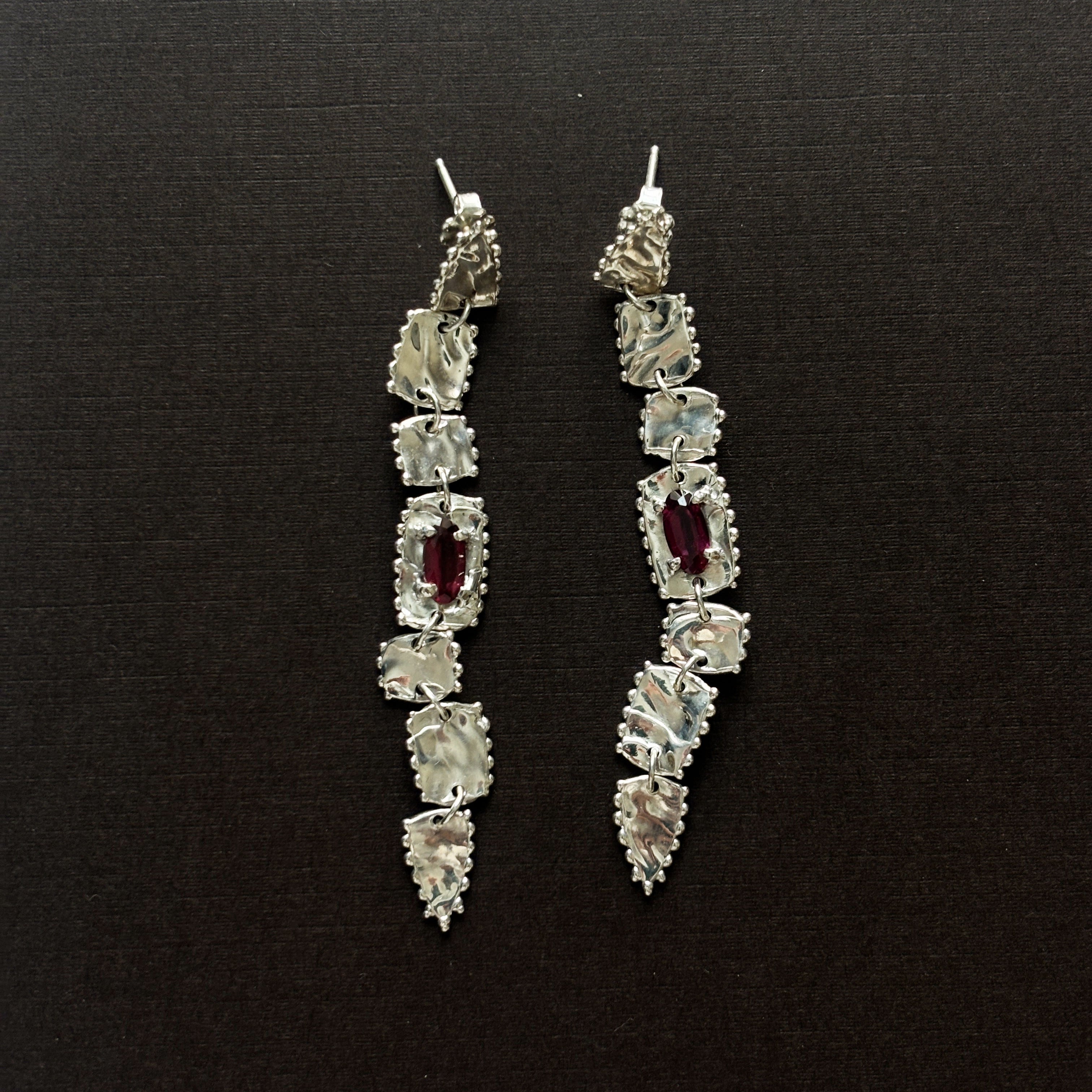 pair of sterling silver long drop earrings  with elongated rhodolite garnets (deep purple/pink) brown background 