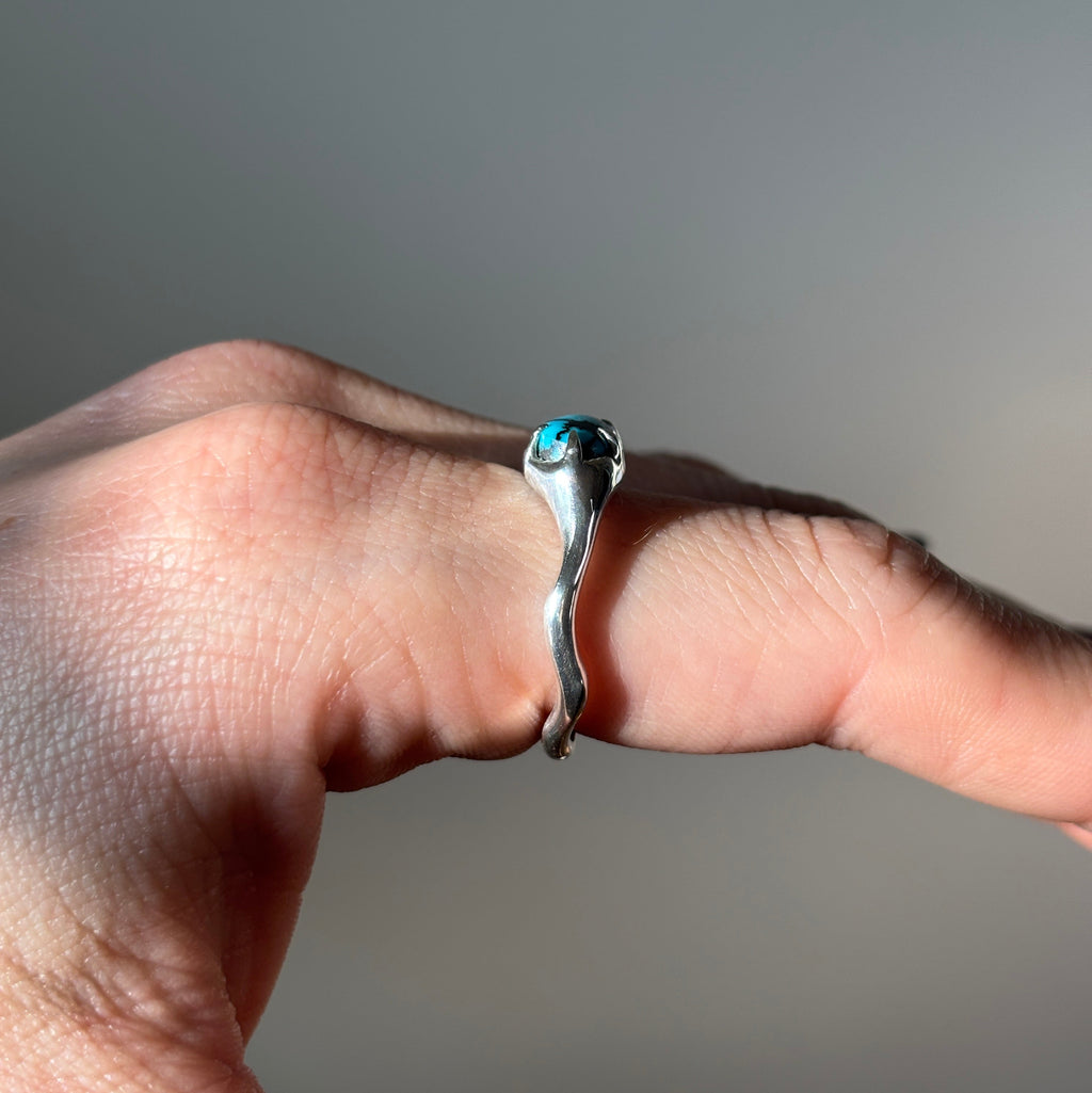 side view of silver turquoise ring on finger. 