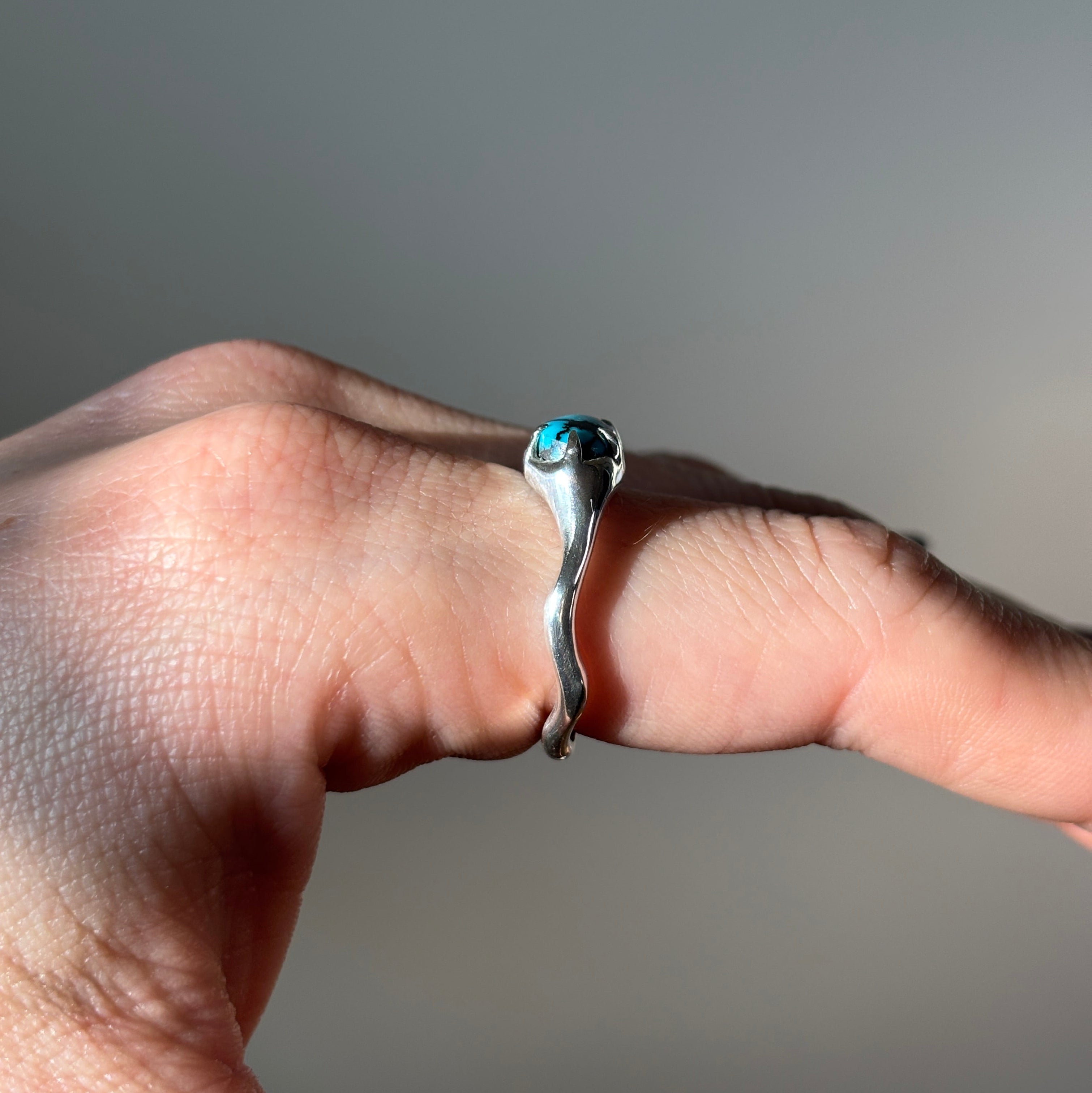 side view of silver turquoise ring on finger. 