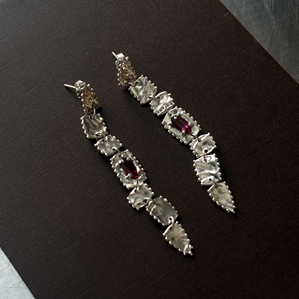 pair of sterling silver long drop earrings  with elongated rhodolite garnets (deep purple/pink) brown background 