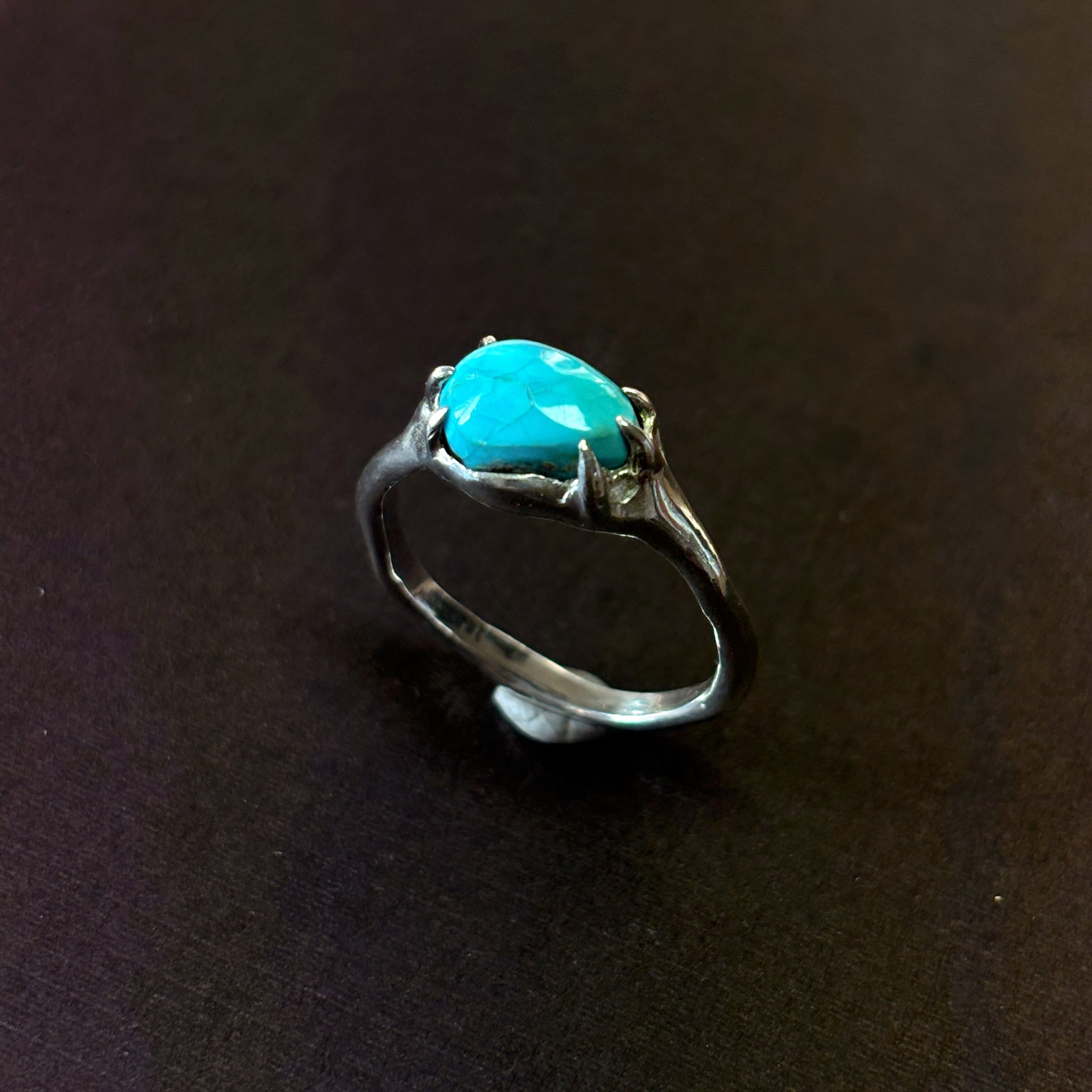 Silver ring with a turquoise stone on a brown background