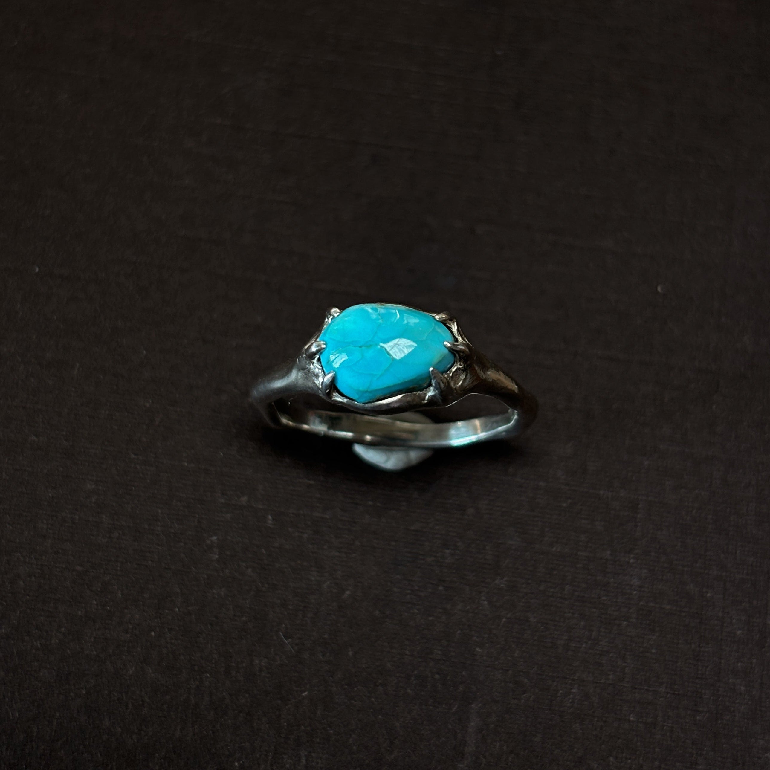 Silver ring with a turquoise stone on a brown background