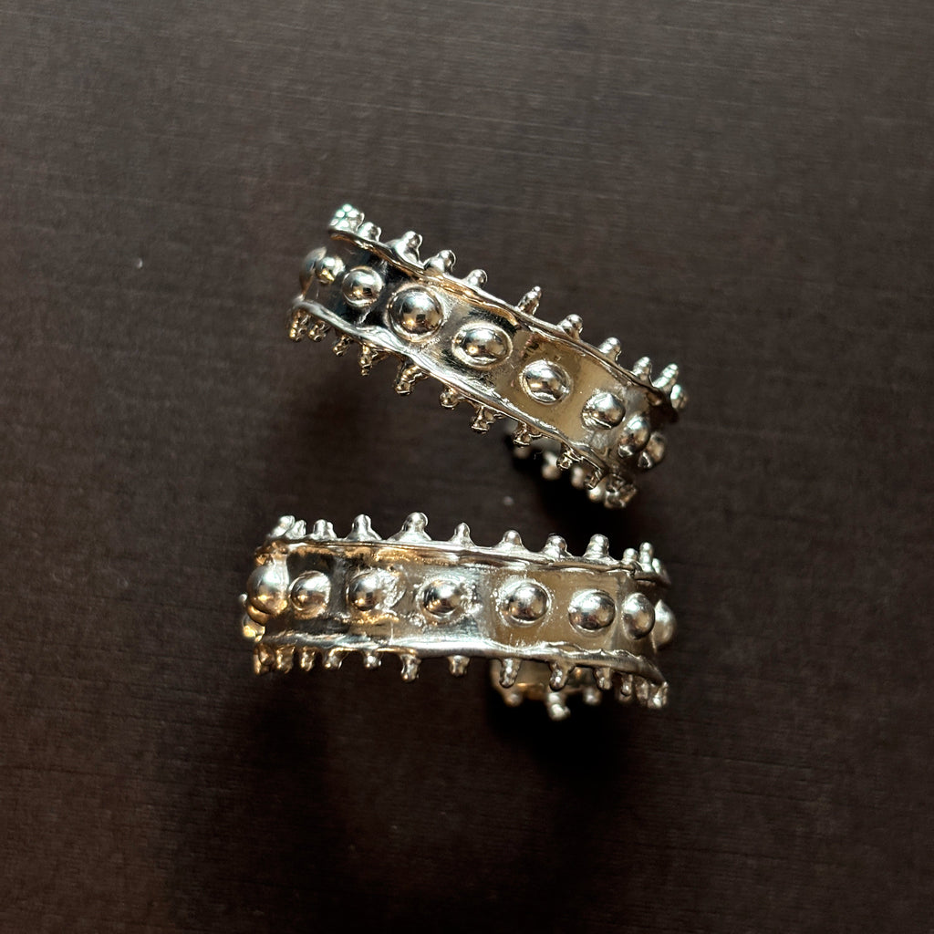 Large textured chunky silver hoops on a brown background. 