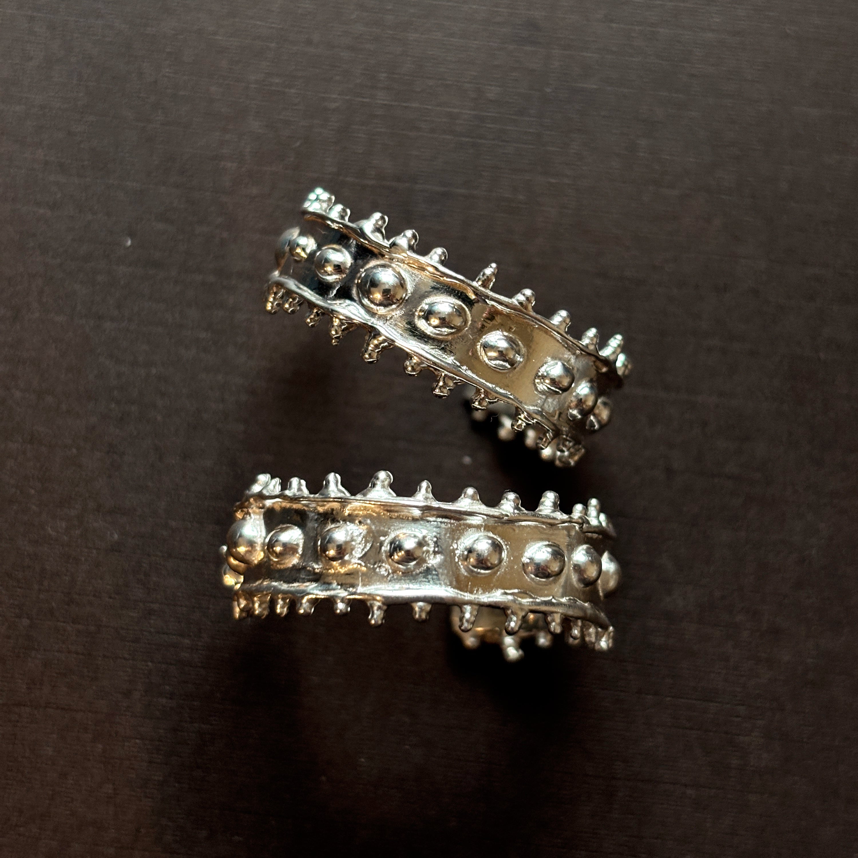 Large textured chunky silver hoops on a brown background. 