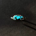 silver and turquoise ring on a brown background.