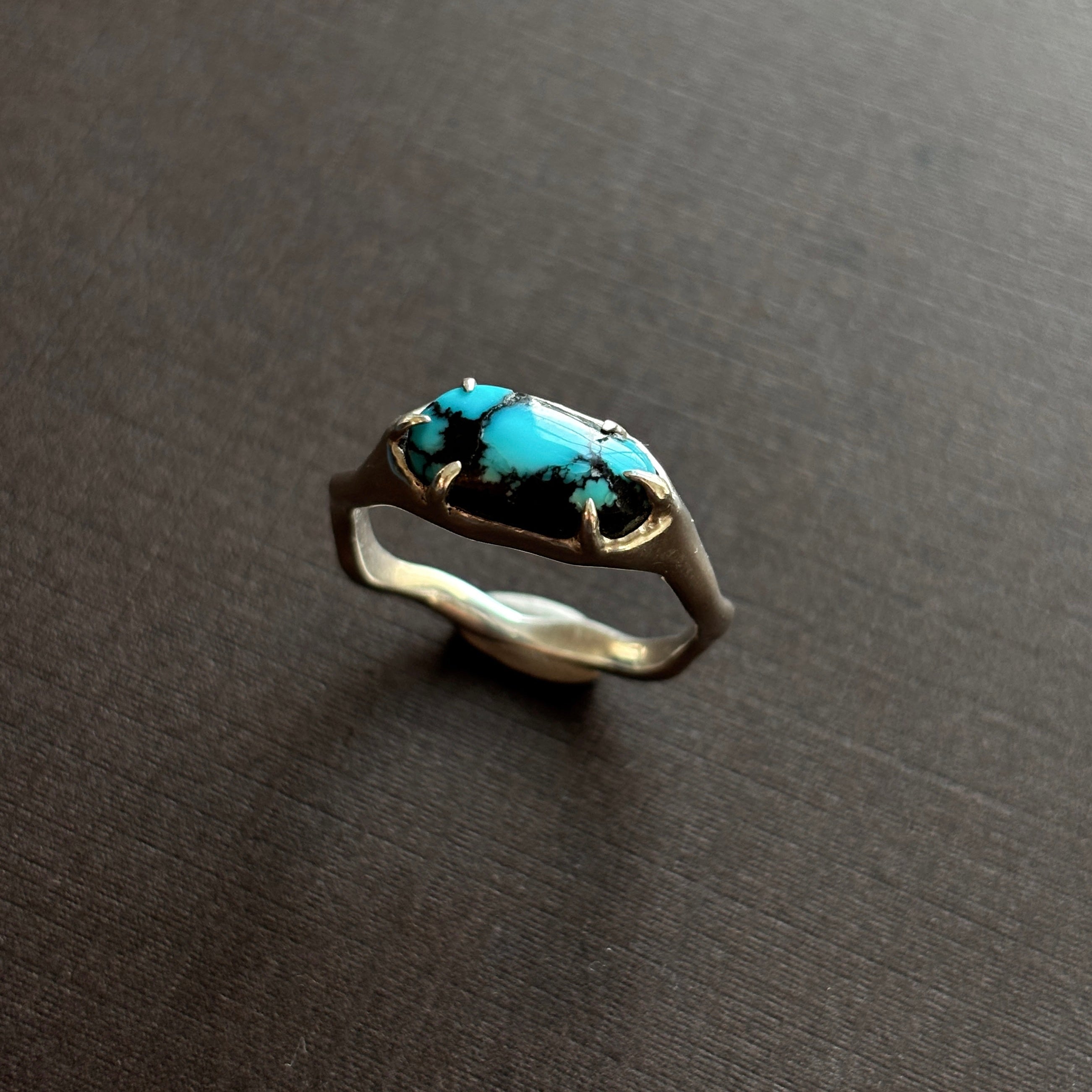 silver and turquoise ring on a brown background.