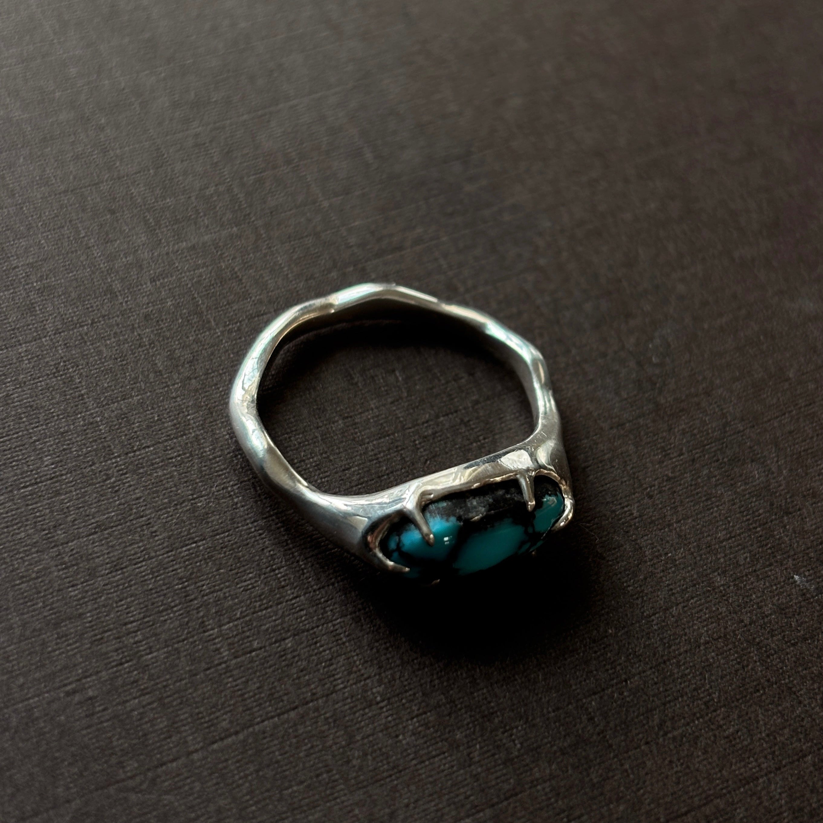 silver and turquoise ring on a brown background.