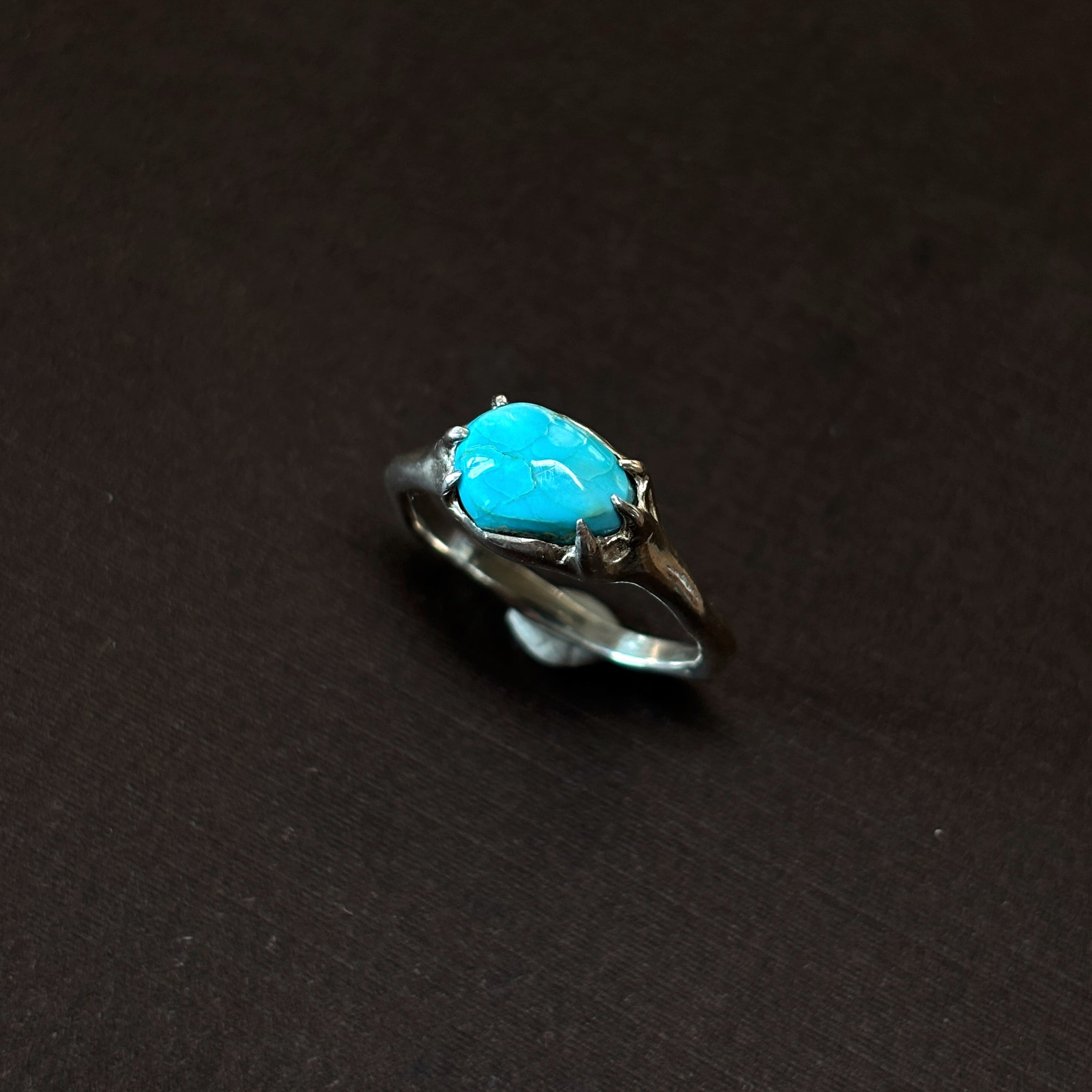 Silver ring with a turquoise stone on a brown background