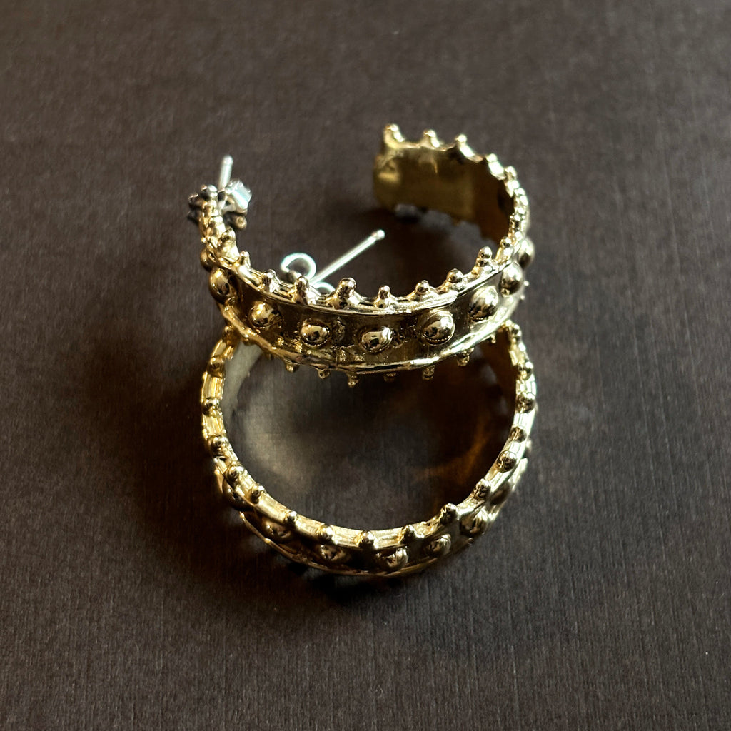 Large chunky textured hoop earring with brown background.