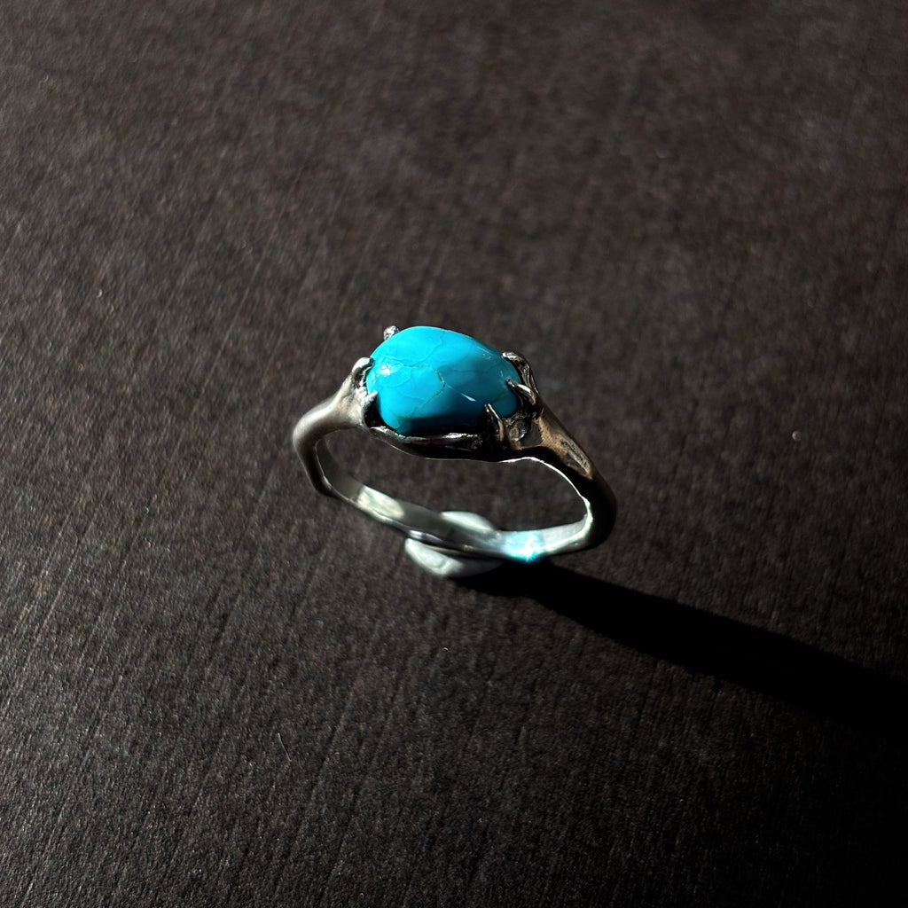 Silver ring with a turquoise stone on a brown background