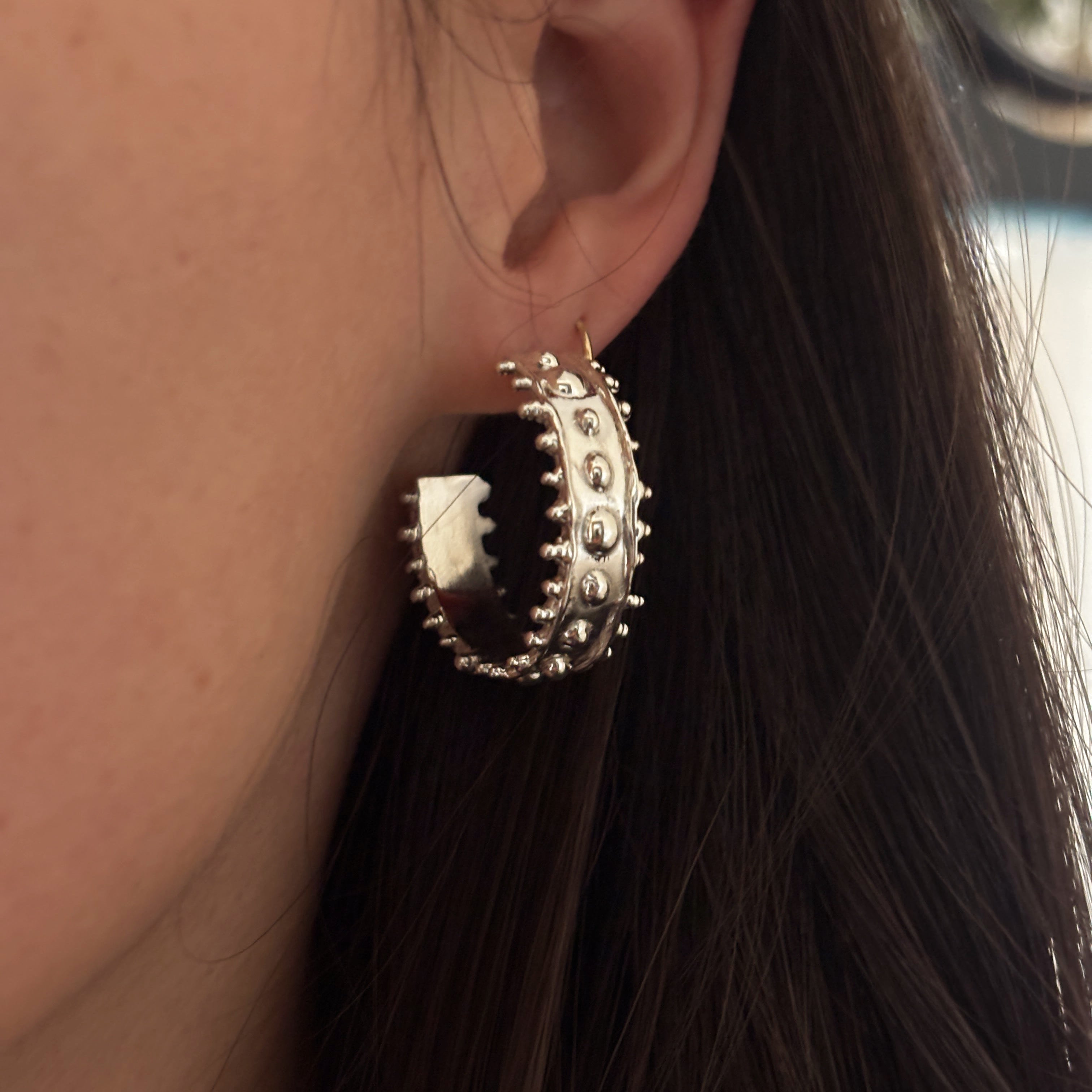 Large chunky silver textured hoop styled on person. 