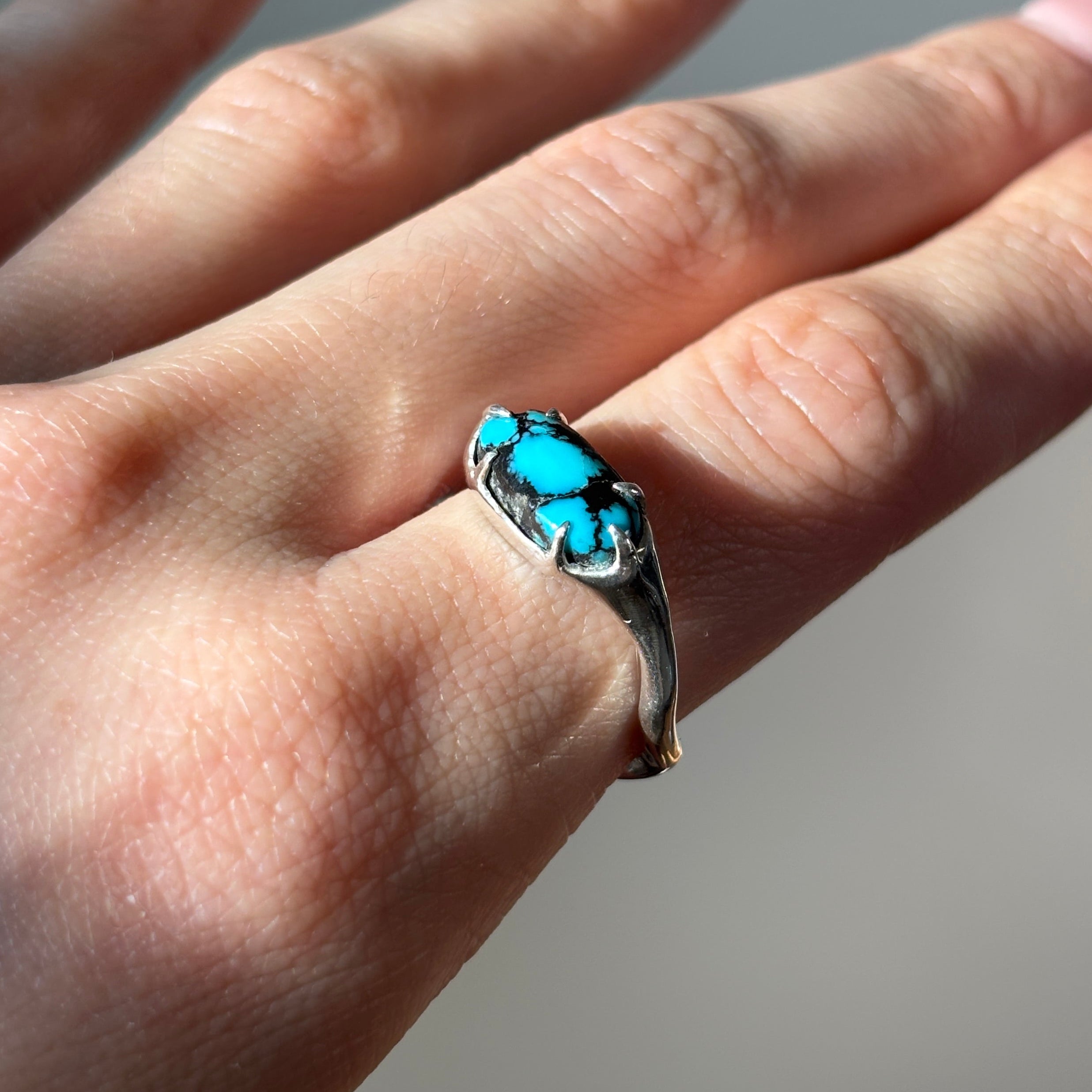 silver and turquoise ring on finger.