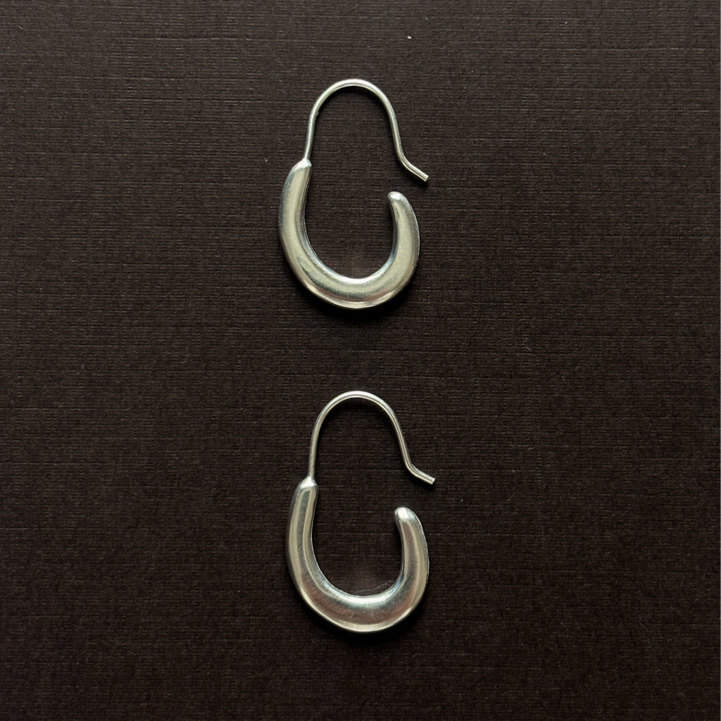 small elongated sterling silver pair of hoop earring on a brown background 