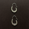 small elongated sterling silver pair of hoop earring on a brown background 