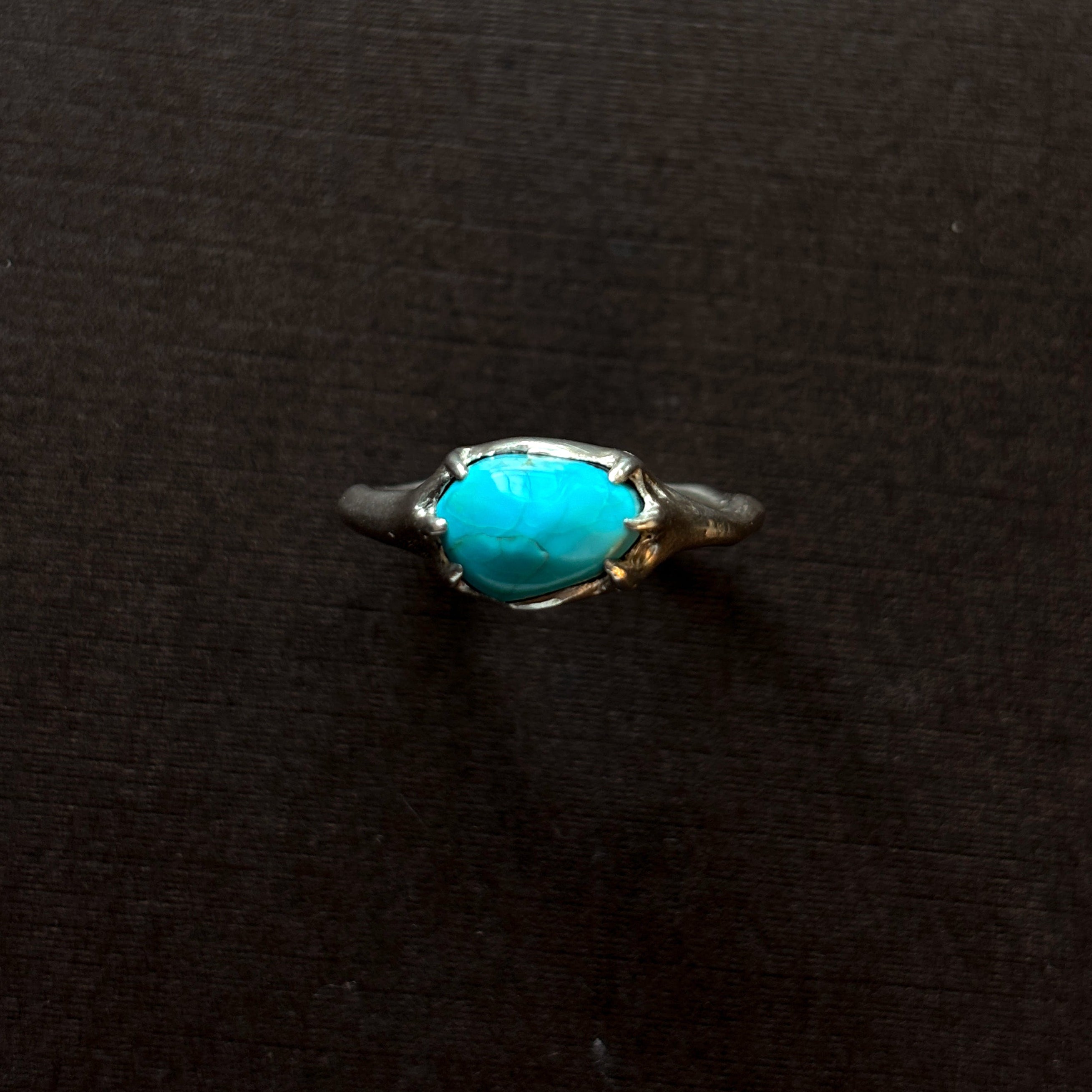 Silver ring with a turquoise stone on a brown background