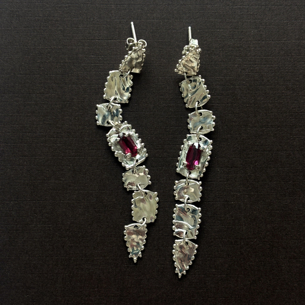 pair of sterling silver long drop earrings  with elongated rhodolite garnets (deep purple/pink) brown background 