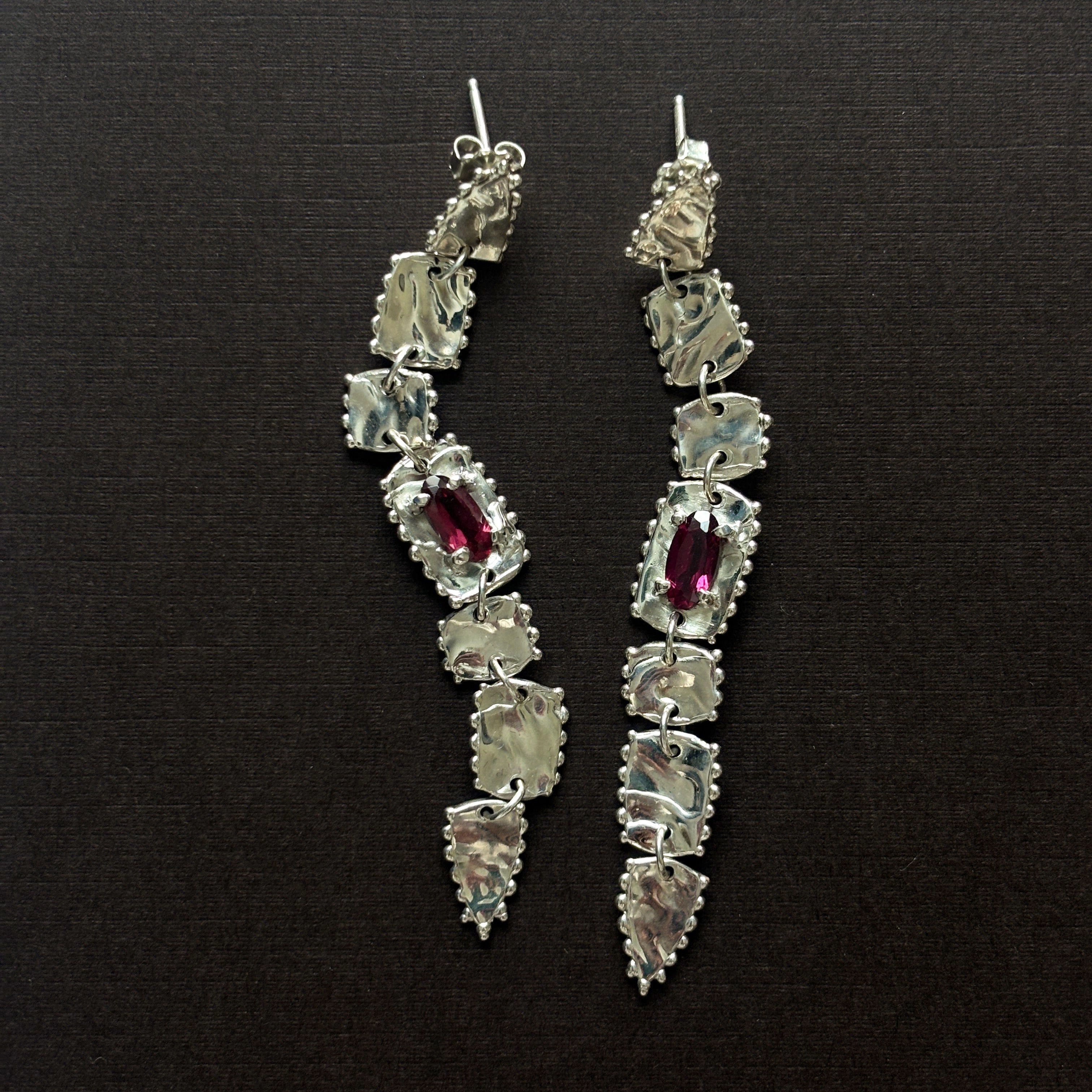 pair of sterling silver long drop earrings  with elongated rhodolite garnets (deep purple/pink) brown background 