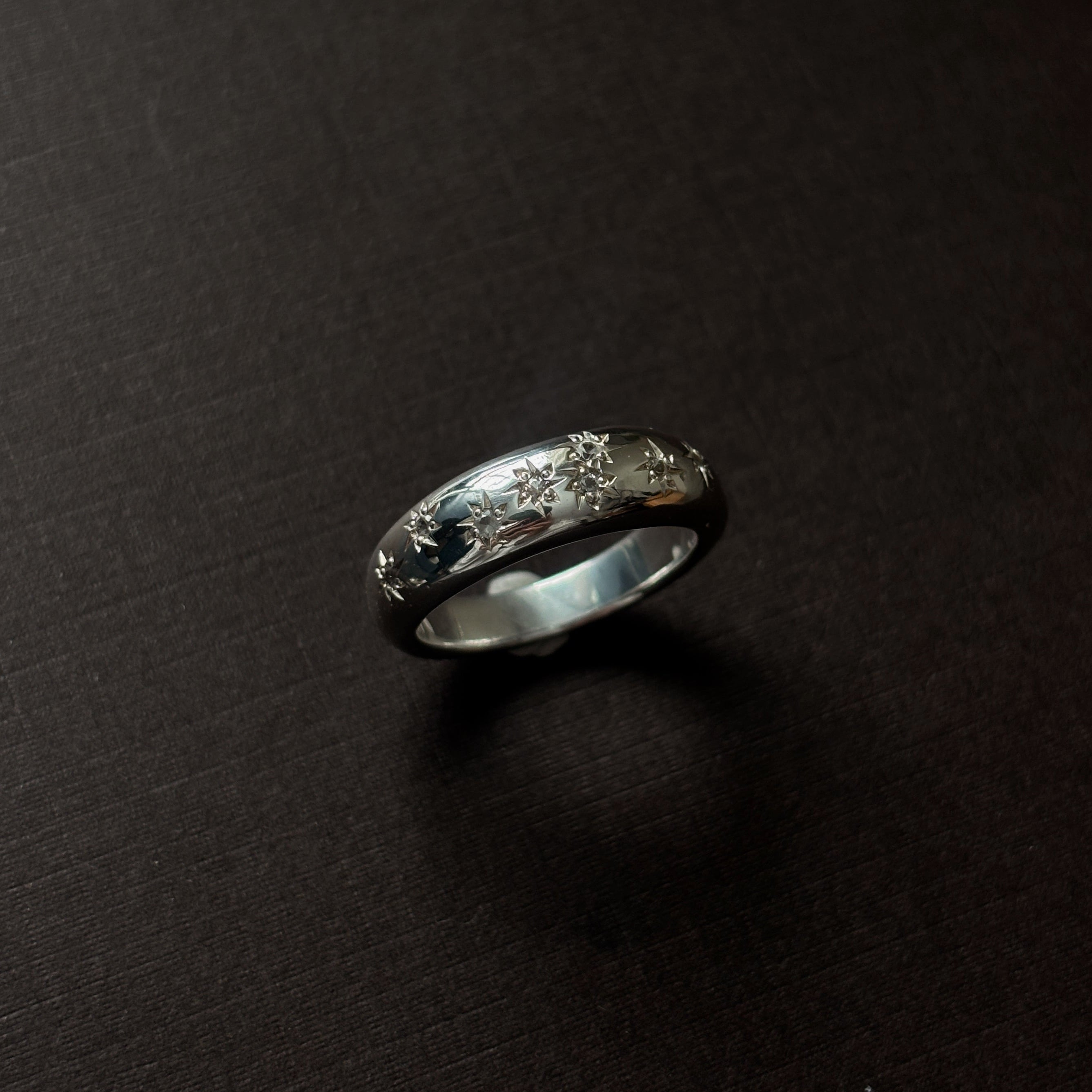 Silver ring with embedded stones on a dark surface