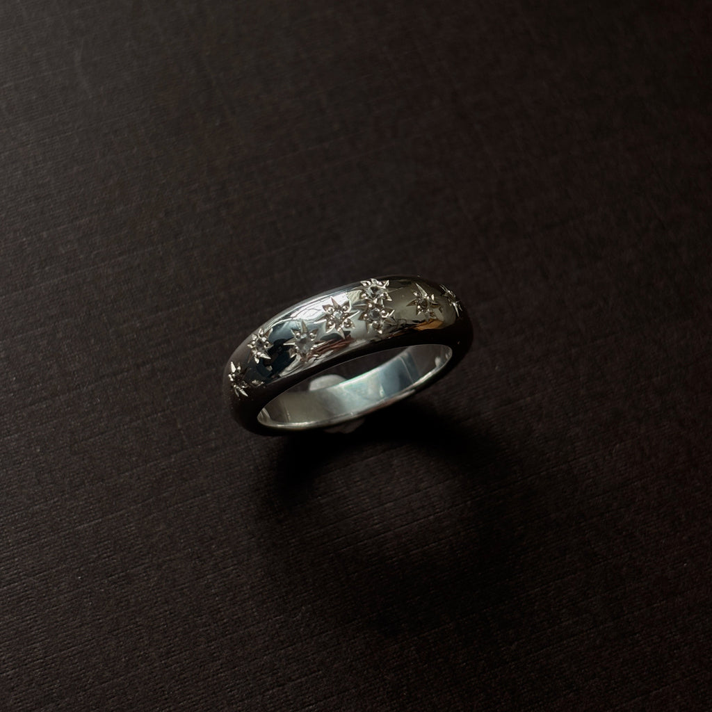 Silver ring with embedded stones on a dark surface