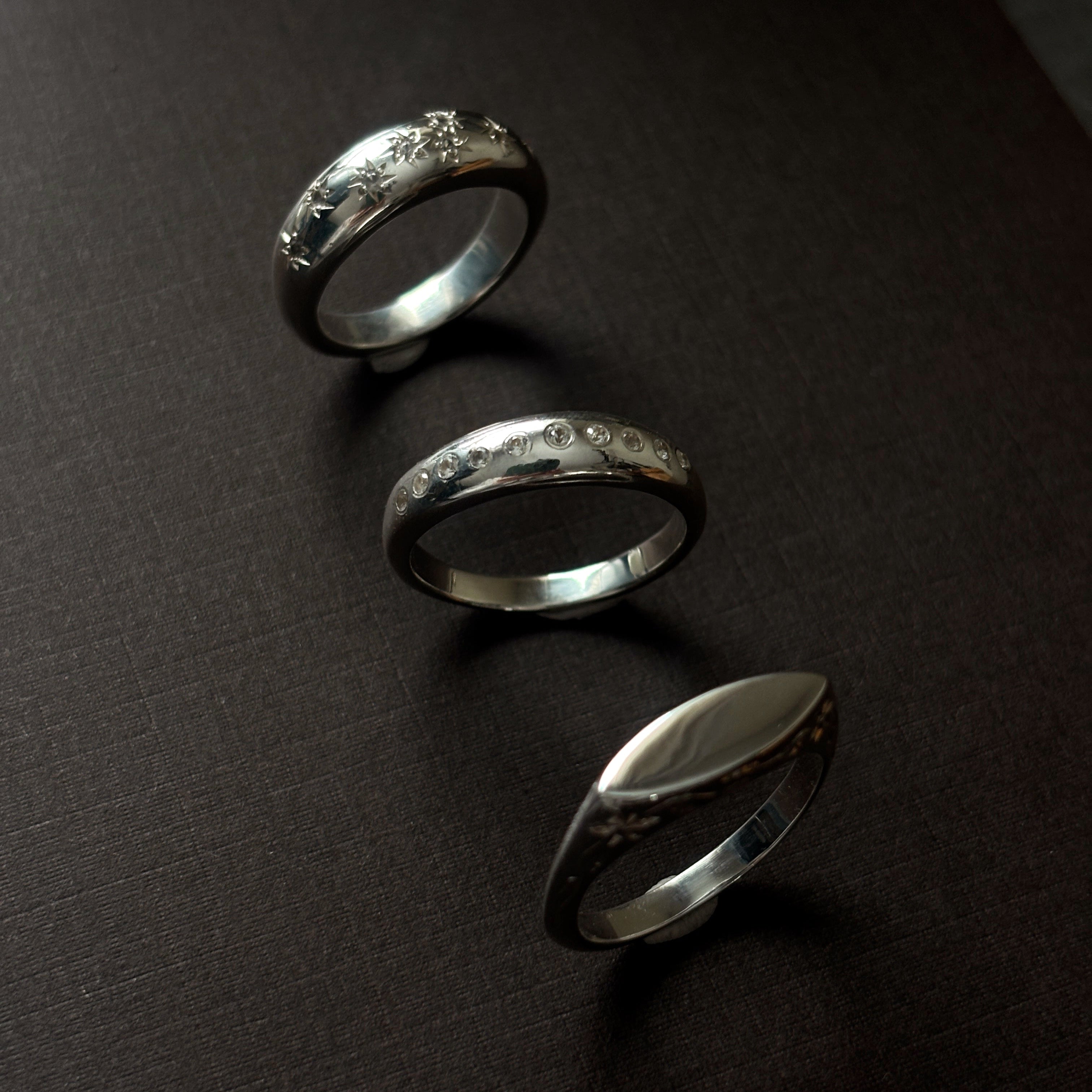 Three silver rings on a dark surface
